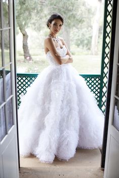 a woman in a white wedding dress standing on the porch with her arms crossed and looking at the camera