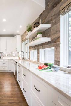 a large kitchen with white cabinets and wood flooring on the walls, along with open shelving