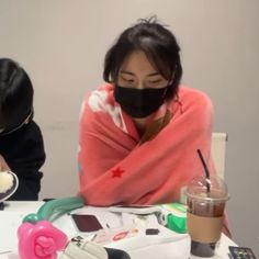 two people sitting at a table wearing face masks