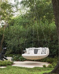 a white swing chair hanging from a tree