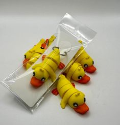 four yellow rubber ducks with orange beaks in plastic package on white table top next to each other