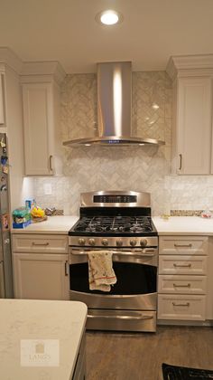 a stove top oven sitting inside of a kitchen next to white cabinets and counter tops