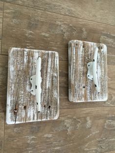 two wooden coasters with white paint on them sitting on a wood floor next to each other