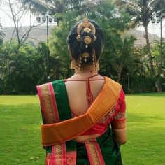 a woman in a green and orange saree standing on top of a lush green field