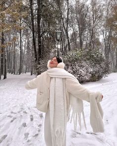 a woman standing in the snow with her arms outstretched