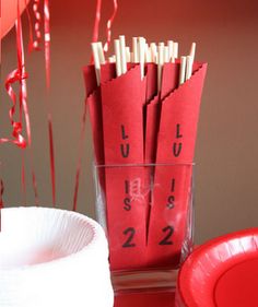 red balloons are in the air next to a cup and some paper straws with numbers on them