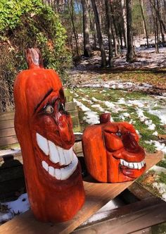 two carved pumpkins sitting on top of a wooden bench