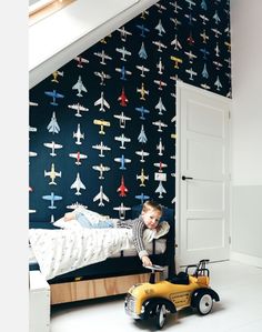 a child's bedroom with wallpaper and toy cars in the foreground, an airplane theme on the wall