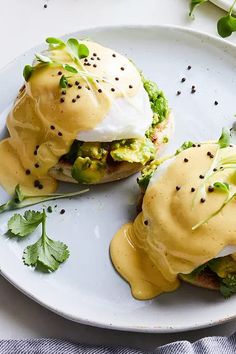 two open faced sandwiches covered in hollandaise and poached eggs on a white plate