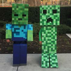 two people made out of paper with creeper and alien faces on them, standing next to each other