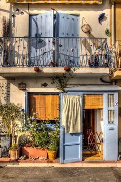 an apartment building with blue shutters on the windows and balconies above it