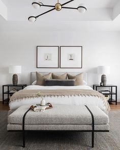 a bedroom with white walls and furniture in the corner, including a bed that has two framed pictures on the wall above it