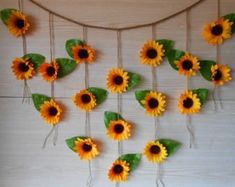 the sunflowers are hanging on the wall with green leafy stems and leaves