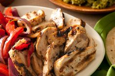 grilled chicken with peppers and onions on a white plate, ready to be eaten