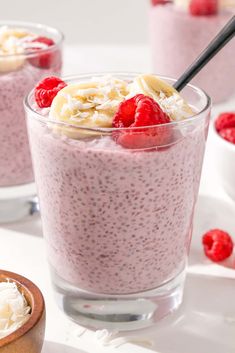 two glasses filled with chia pudding and topped with raspberries