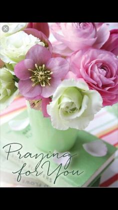 a vase filled with pink and white flowers on top of a green table cloth next to a stack of books