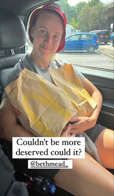 a woman sitting in the back seat of a car holding a paper bag