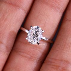 a woman's hand holding an engagement ring with a diamond in the center and two diamonds on each side