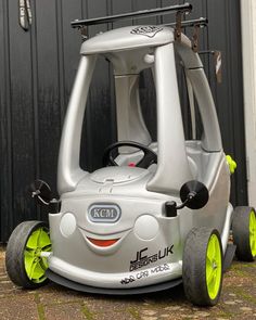 an electric car is parked in front of a garage door with yellow wheels and rims