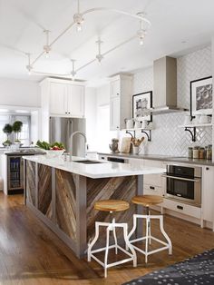 a kitchen with an island and stools in the center, surrounded by white cabinets