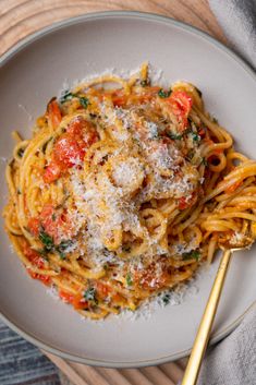 a white plate topped with pasta covered in sauce and parmesan cheese next to a fork