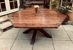 a wooden table sitting on top of a tiled floor next to a building with windows