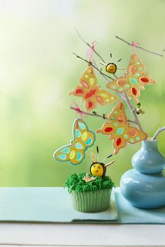 a cupcake sitting on top of a table next to a vase filled with butterflies