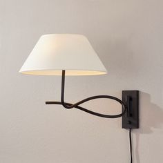 a wall lamp with a white shade on it's side next to a light switch