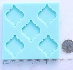 a penny sitting next to a plastic mold that is shaped like an arab pattern and has been cut into smaller shapes