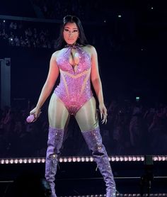 a woman in a bodysuit standing on stage with her legs spread out and wearing thigh high boots