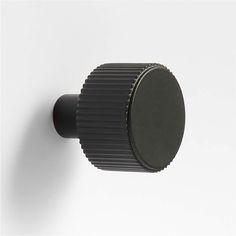 a black knob on the side of a white wall with an object in the middle