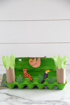 a green tray with animals and trees on it sitting on a table next to a white wall