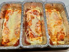 three pans filled with lasagna casserole sitting on top of a counter