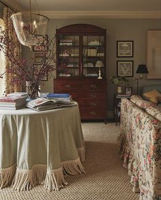 a living room filled with furniture and a table covered in a white cloth next to a window