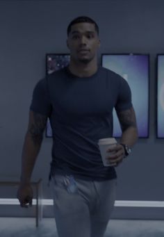 a man holding a coffee cup while standing in front of three pictures on the wall