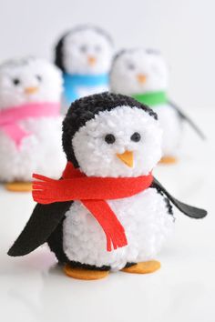 small crocheted penguins with red scarfs and hats on their heads, standing next to each other