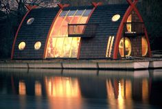 a boat house is lit up at night on the water's edge with windows