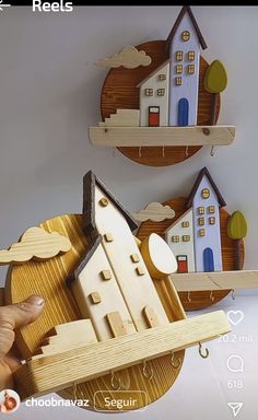 a wooden model of a house on a shelf with two other houses in the background