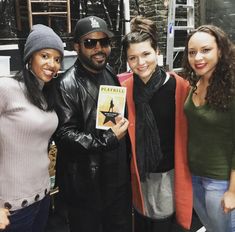 three women and a man are posing for a photo in front of a book store