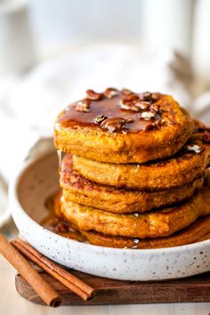 stack of pumpkin pancakes with maple syrup and pecans on the side, ready to be eaten