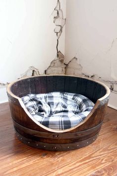 a dog bed made out of an old barrel is sitting on the floor next to a wall