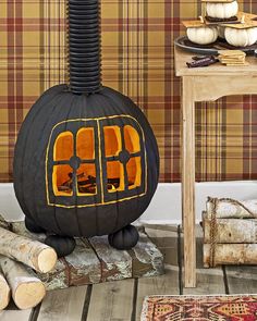 a pumpkin shaped fireplace in the middle of a room with logs on the floor and plaid wallpaper behind it