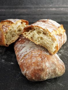 two loaves of bread sitting on top of a black counter next to each other