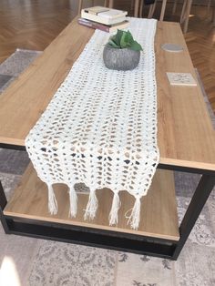 a table with a white crocheted runner on it and some books in the background