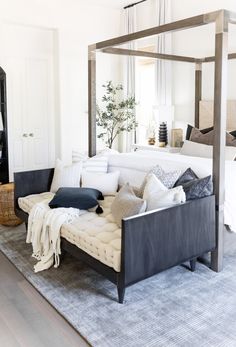 a white bed sitting on top of a wooden floor next to a couch in a bedroom