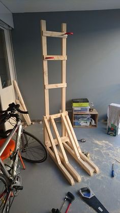 a bicycle parked next to a ladder in a room with other items on the floor