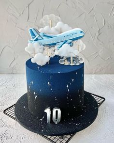 a blue and black cake with an airplane topper on it's bottom tier