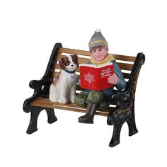 a figurine is sitting on a bench reading a book with a dog next to it