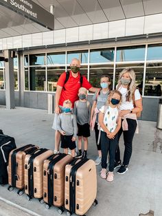 a group of people standing next to suitcases in front of an airport terminal with masks on