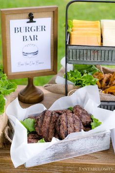 a burger bar with lettuce and other foods on the table in front of it